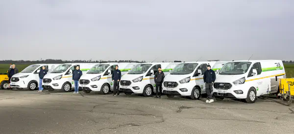 The PJB Technical Services field team standing beside their fleet of branded Ford Transit Custom vans, ready for specialist site testing and materials verification across the UK.